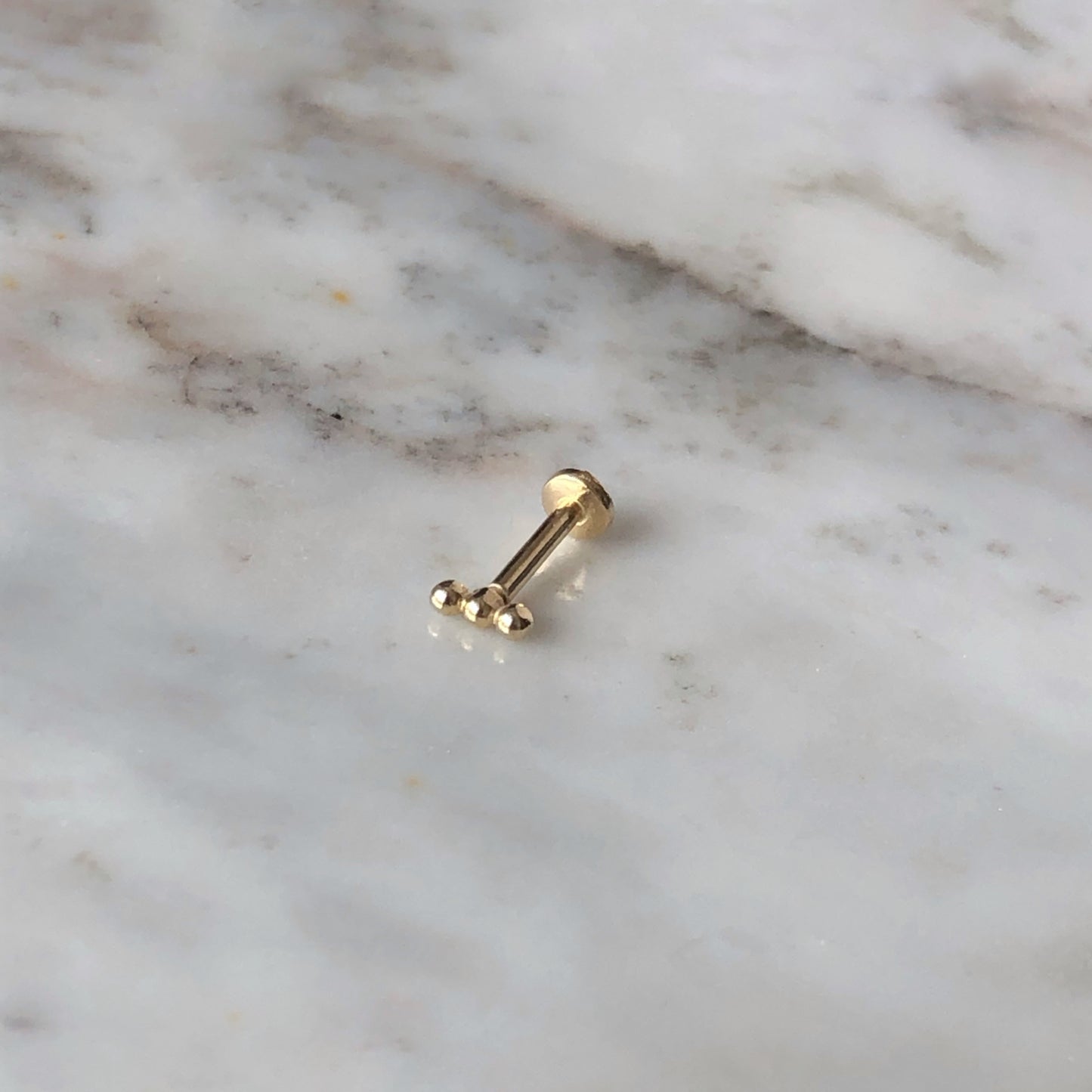 Aretes single en oro amarillo 14k de 3 bolitas y rosca interna para piercing
