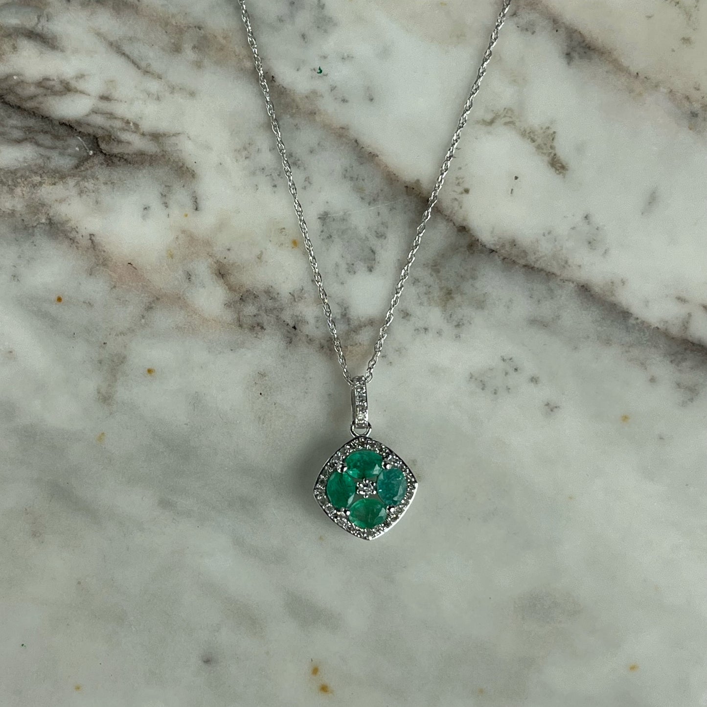 Collar en oro blanco 14k con dije de esmeraldas en forma de flor y borde de diamantes 0.15ctw