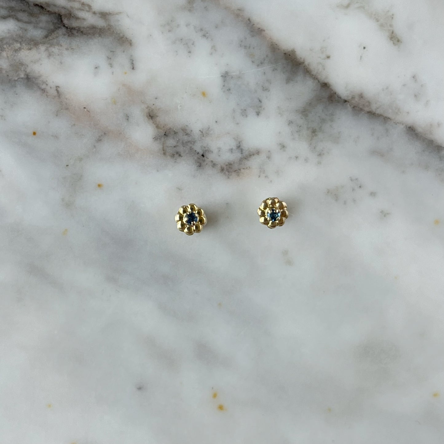 Aretes en oro amarillo 14K con flor de pétalos de oro y circonita azul en el centro con tope a rosca