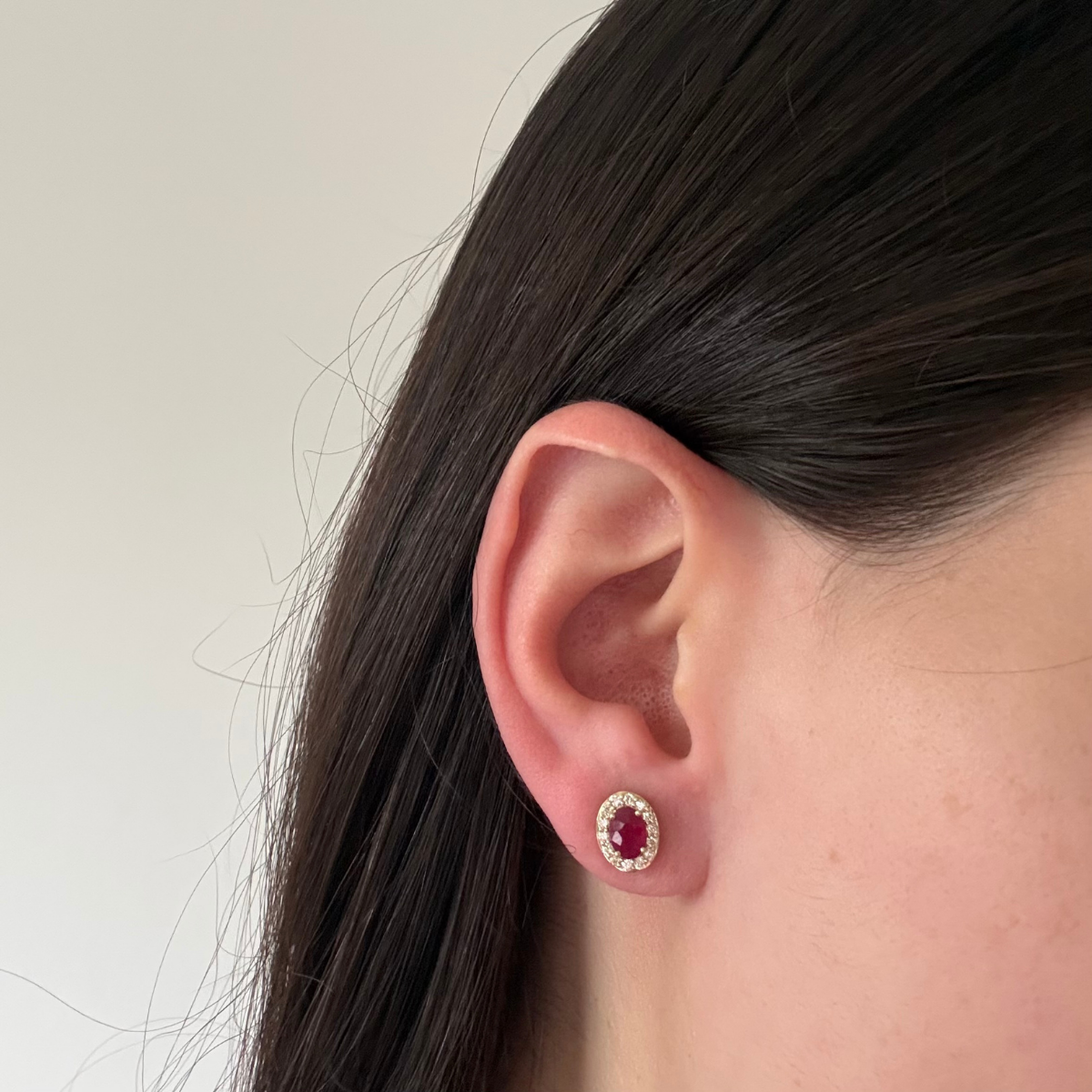 Arete en oro amarillo 10K con rubíes ovalados y halo de diamantes 0.35ctw con broche a rosca