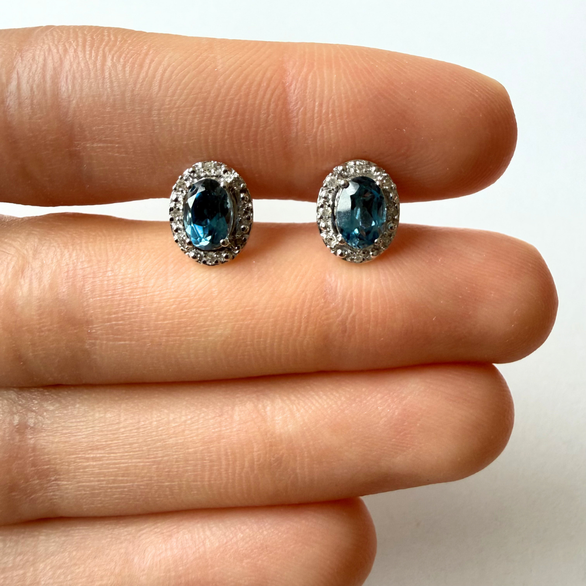 Aretes en oro blanco 10K con topacio london blue ovalado y halo de diamantes 0.09ctw