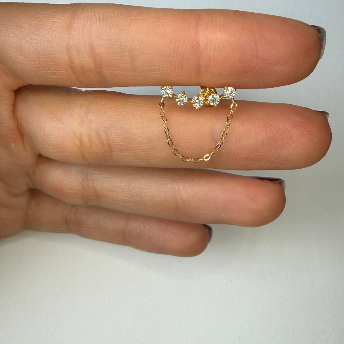 Arete curva de cinco diamantes de laboratorio con cadena en oro amarillo 18k