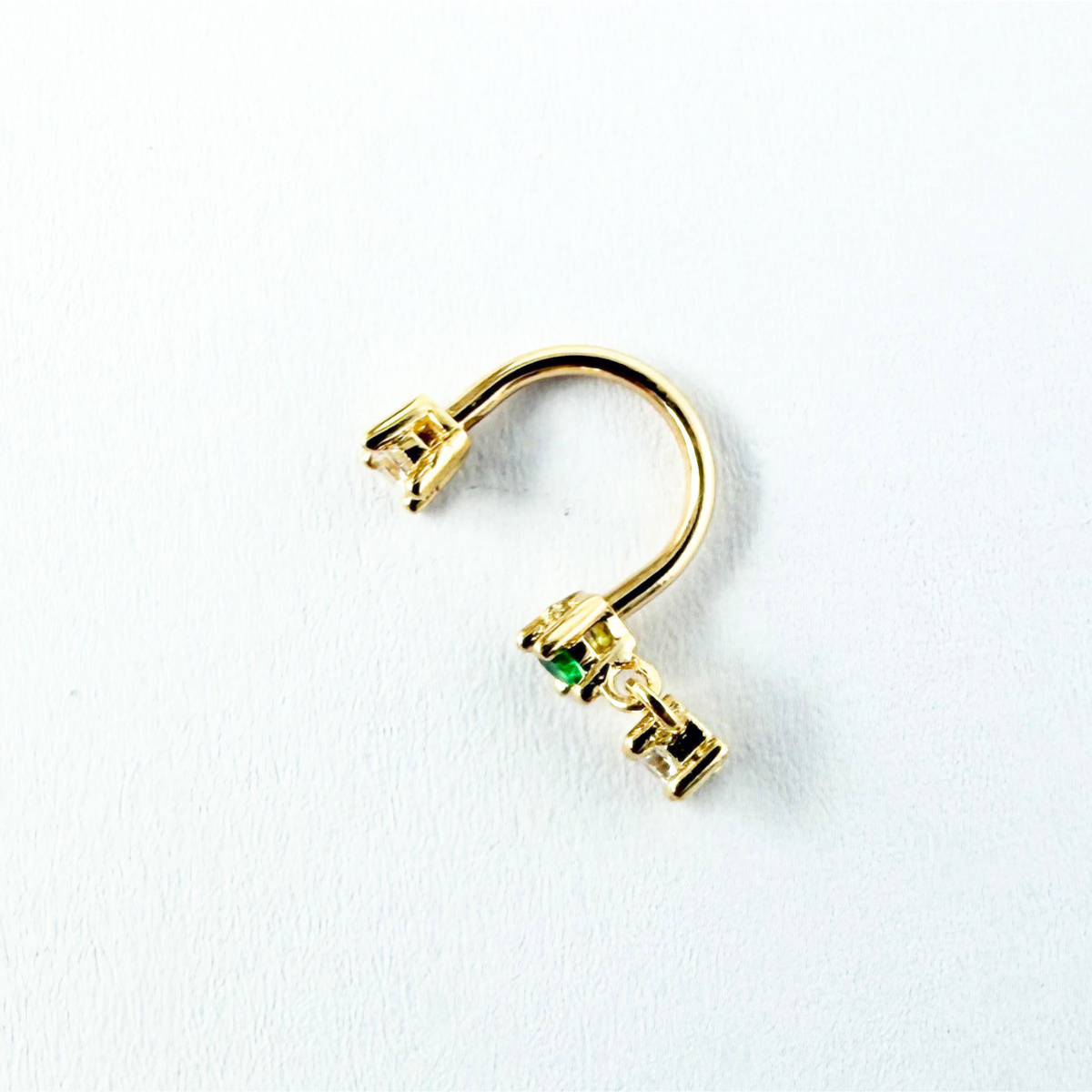 Arete piercing curva en oro amarillo 14k con circonitas blancas y verde