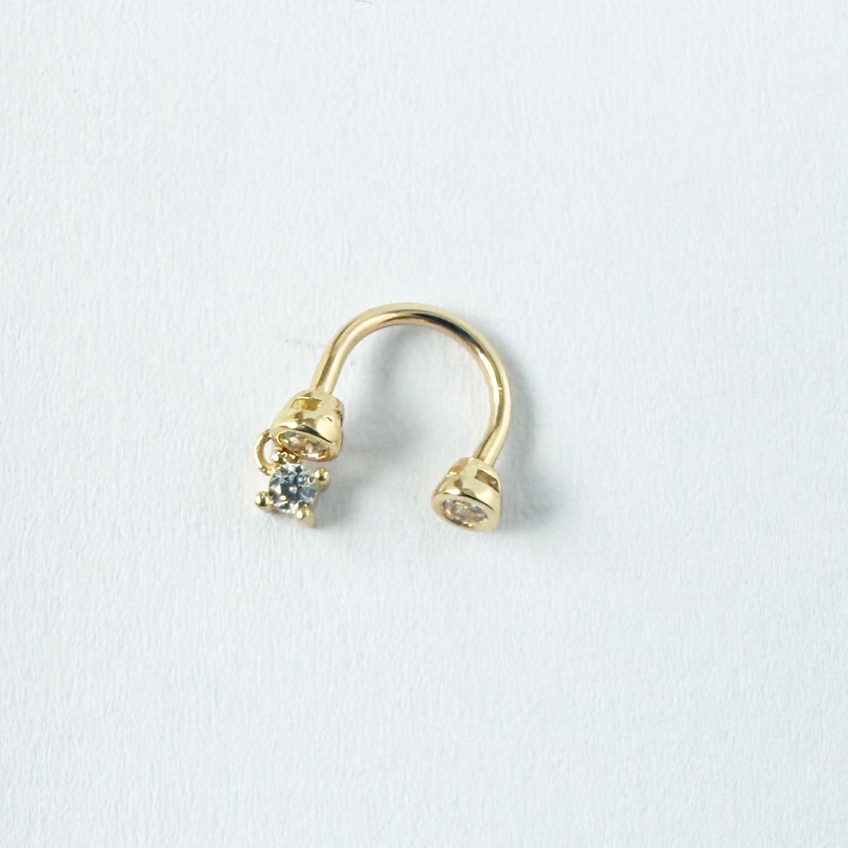 Arete piercing curva en oro amarillo 14k con tres circonitas