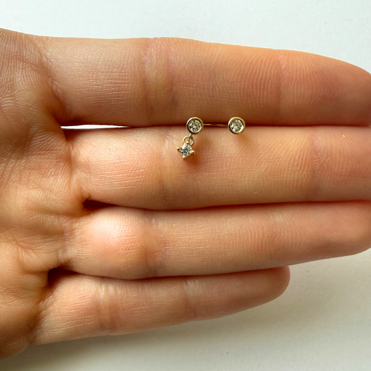 Arete piercing curva en oro amarillo 14k con tres circonitas