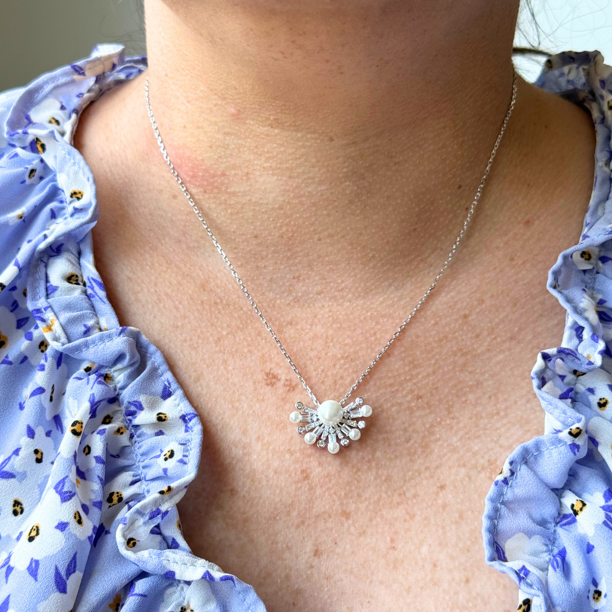 Collar de plata con baño platino y media flor de perla en el centro y circonitas blancas