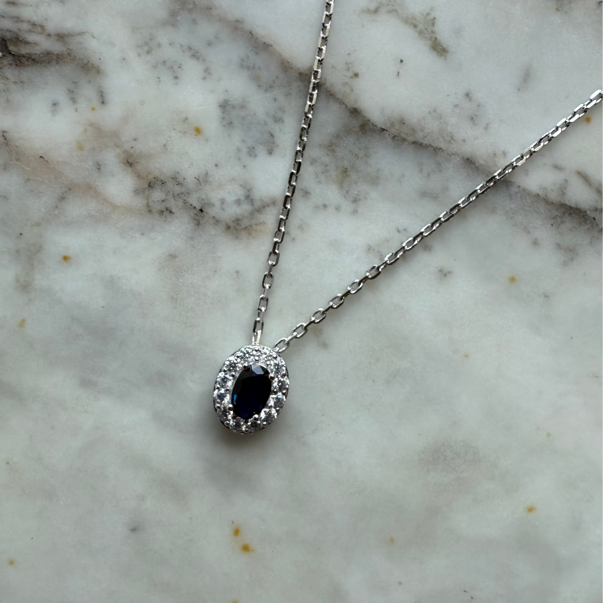 Collar de plata con baño platino y circonita ovalada azul con halo de circonitas blancas