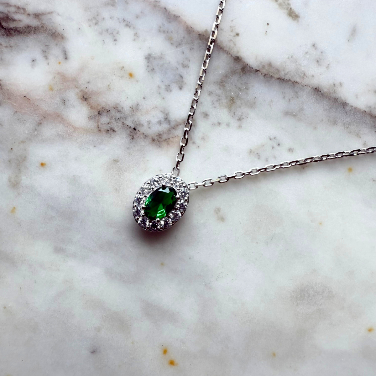 Collar de plata con baño platino y circonita ovalada verde con halo de circonitas blancas.