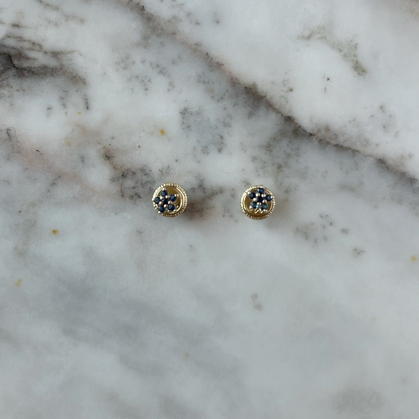 Aretes en oro amarillo de 14K con mini flor de circonitas azules con agarres con tope rosca