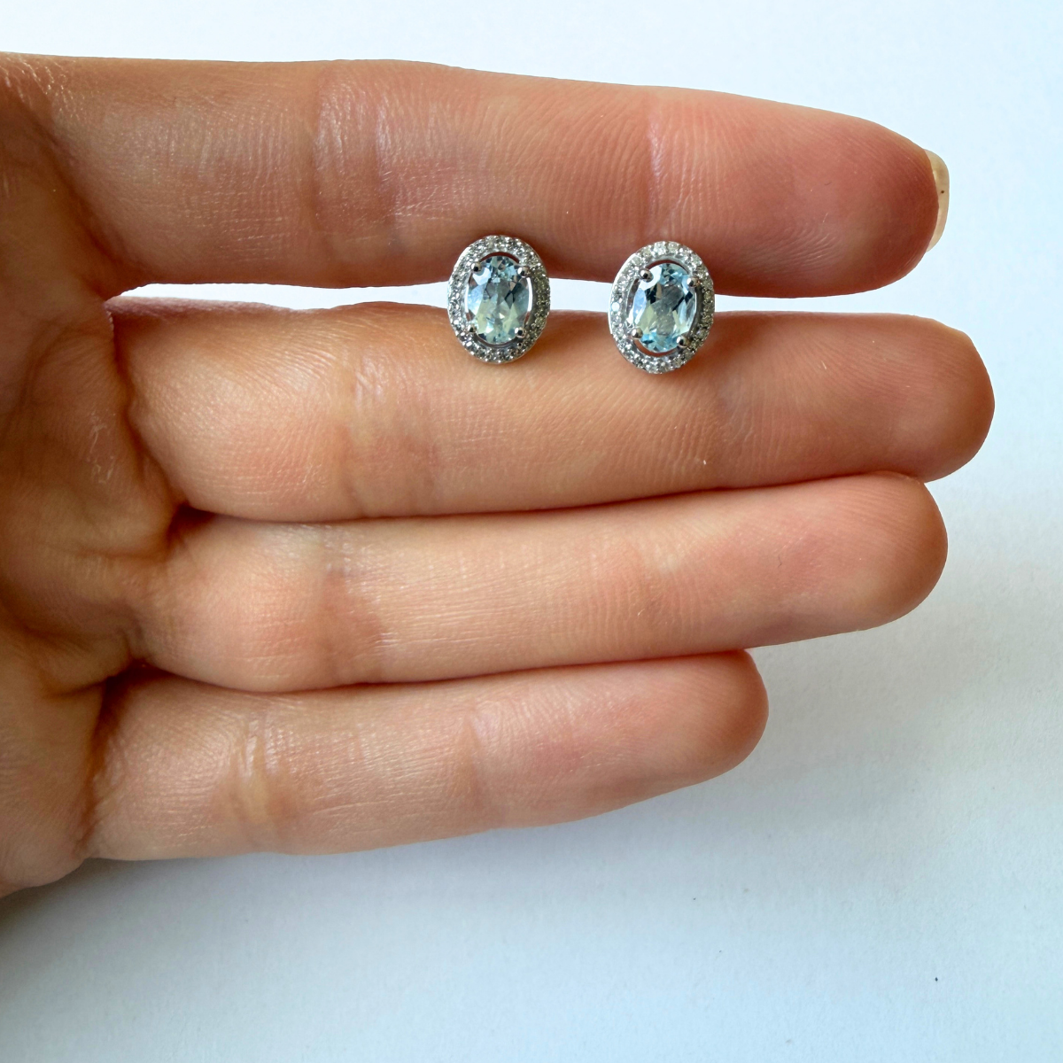 Aretes en oro blanco 14k con aquamarina ovalada y halo de diamantes 0.18ctw