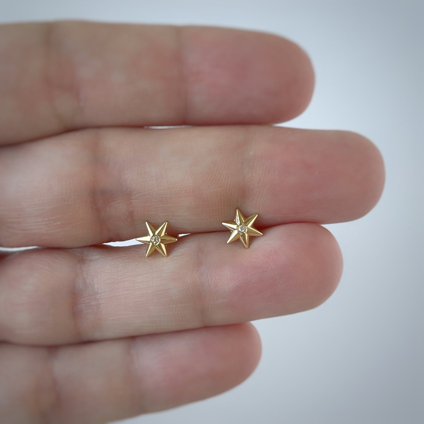 Aretes en oro amarillo 14K con estrella de 6 puntas y circón blanco en el centro con tope rosca