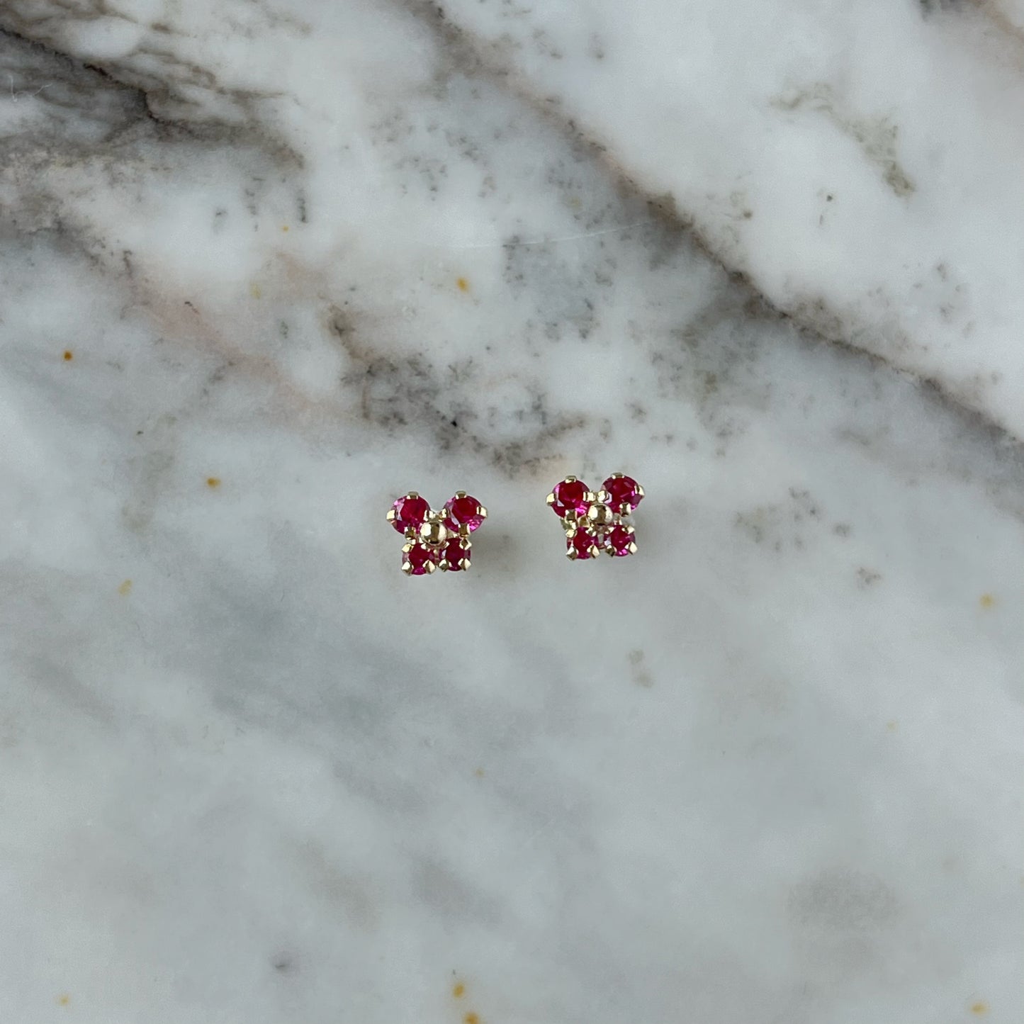 Aretes en oro amarillo 14K con mariposa con circonita fucsia y bolita de oro en el centro con tope rosca