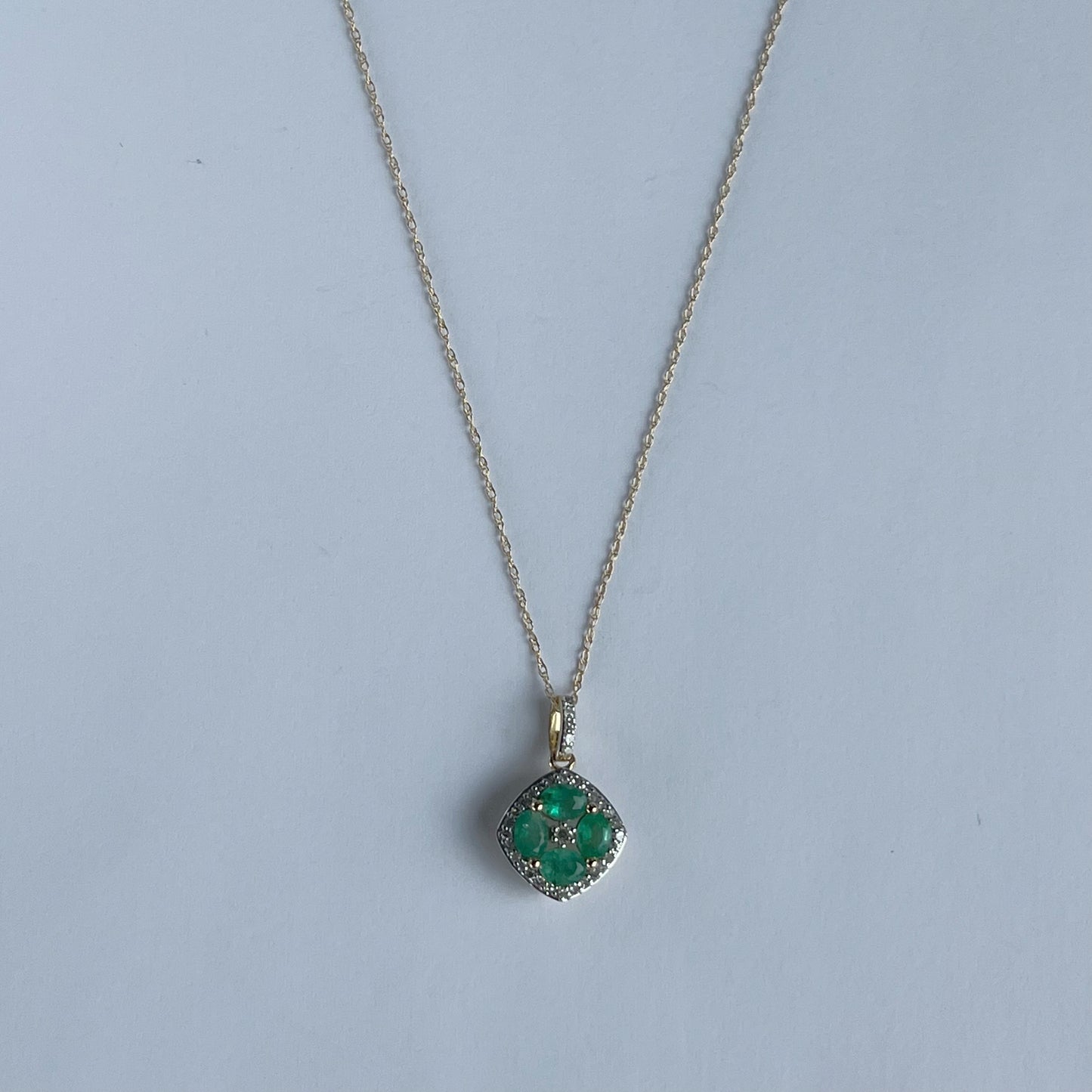 Collar en oro amarillo 14k con dije de esmeraldas en forma de flor y borde de diamantes 0.15ctw