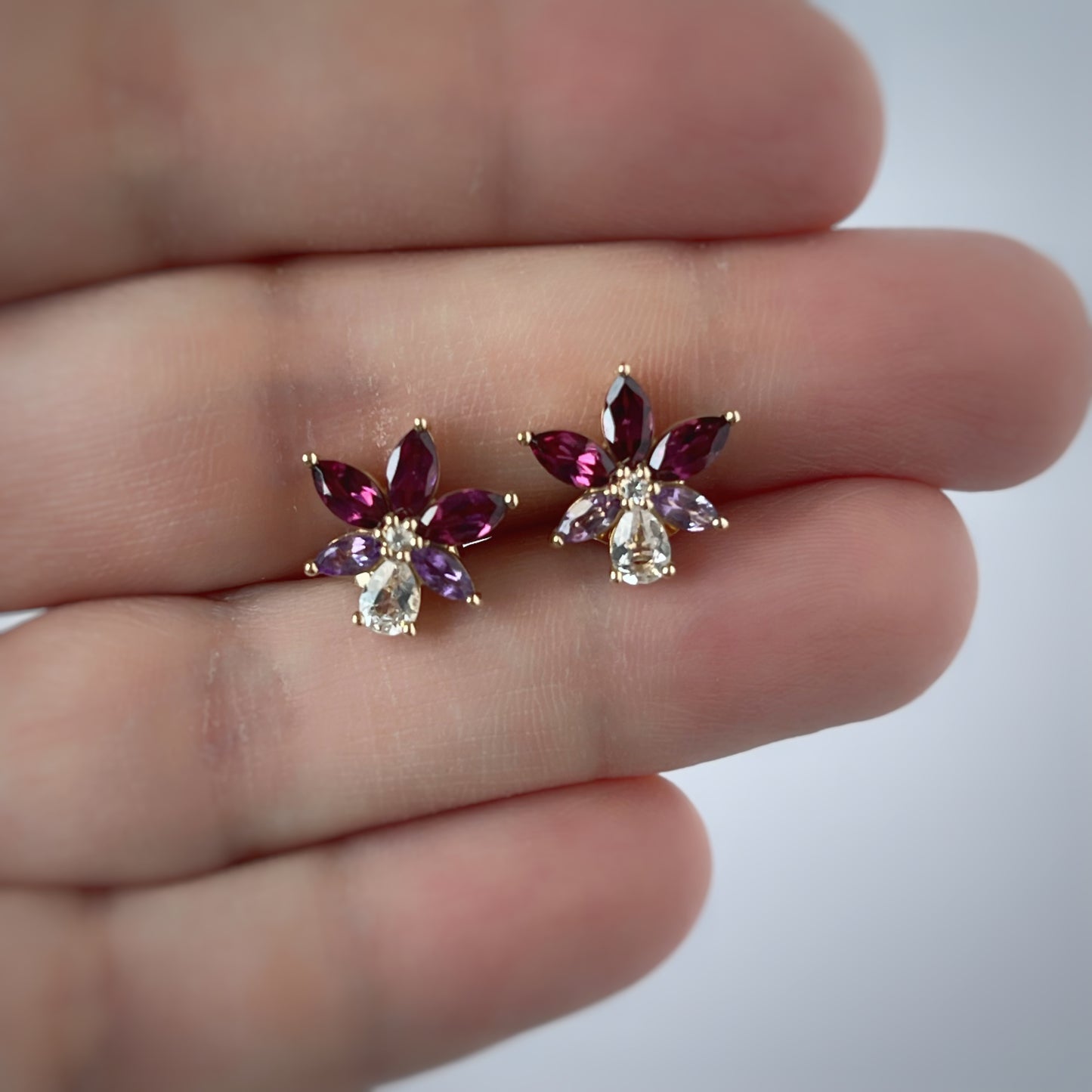 Aretes en oro amarillo 14k con petalos de topacio blanco y granate rhodolite