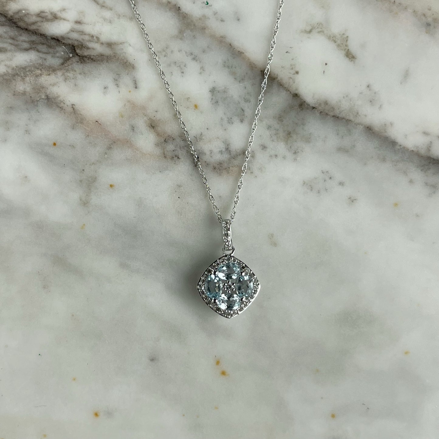 Collar en oro blanco 14k con dije de aquamarinas en forma de flor y borde de diamantes 0.15ctw