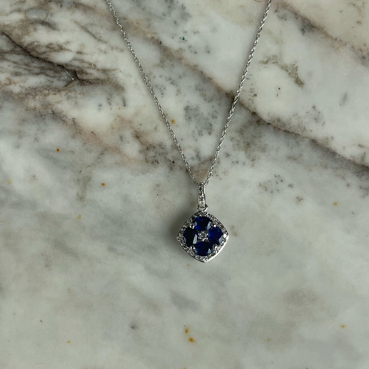 Collar en oro blanco 14k con dije de zafiros en forma de flor y borde de diamantes 0.15ctw