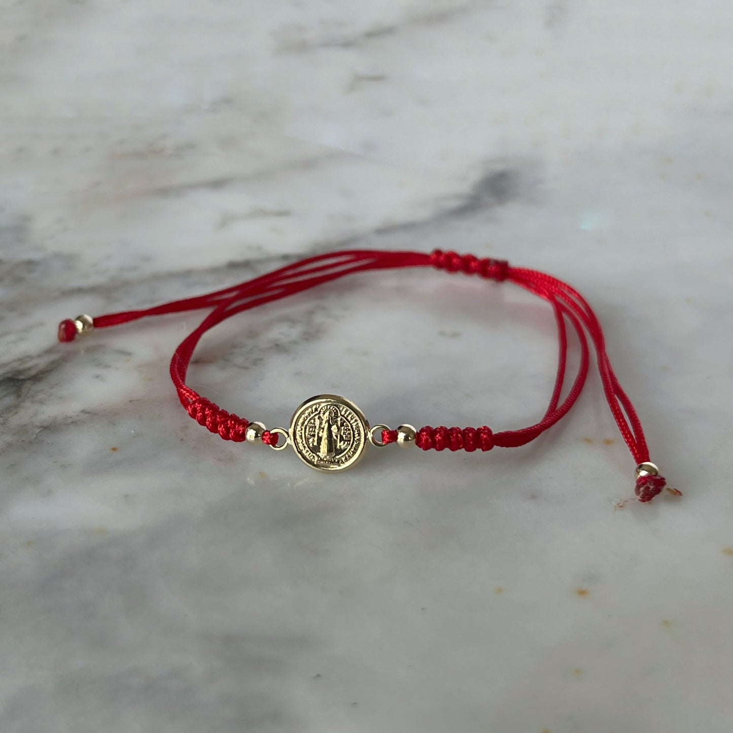 Pulsera de San benito en oro amarillo de 14K con cordón rojo