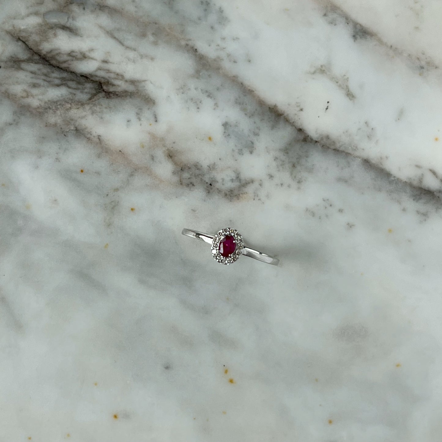 Anillo en oro blanco 10k con rubí ovalado y halo de diamantes 0.10ctw