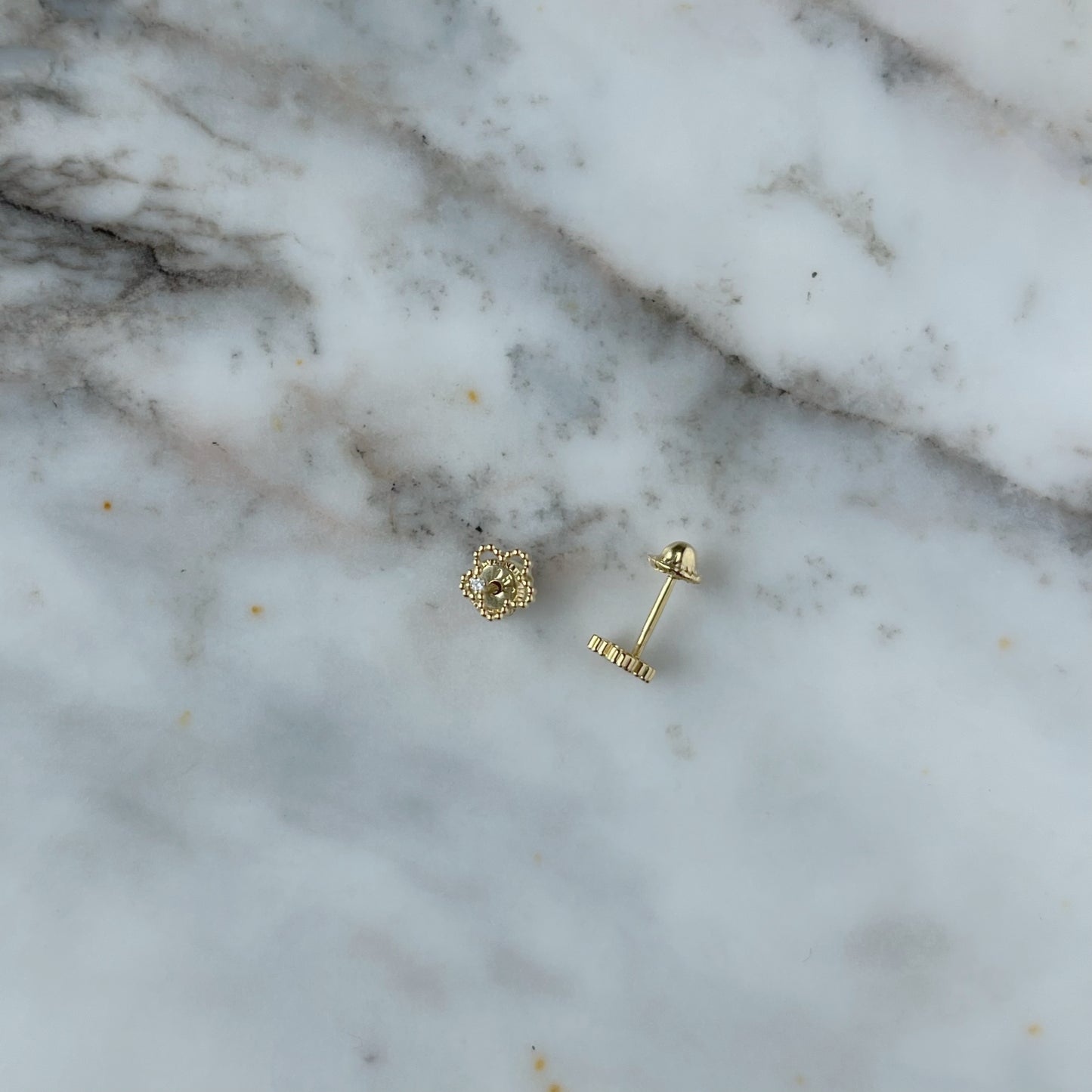 Aretes en oro amarillo 18k flor delineada con diamante con broche rosca