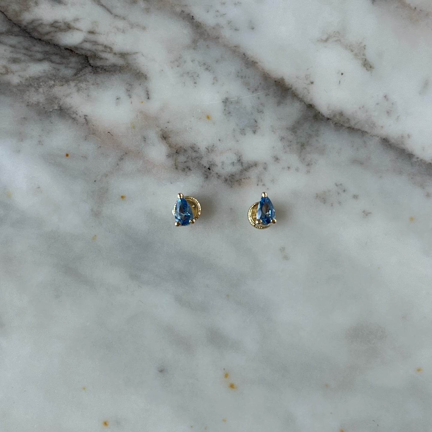 Aretes en oro amarillo 14K en forma de gota con circonita azul con tope rosca