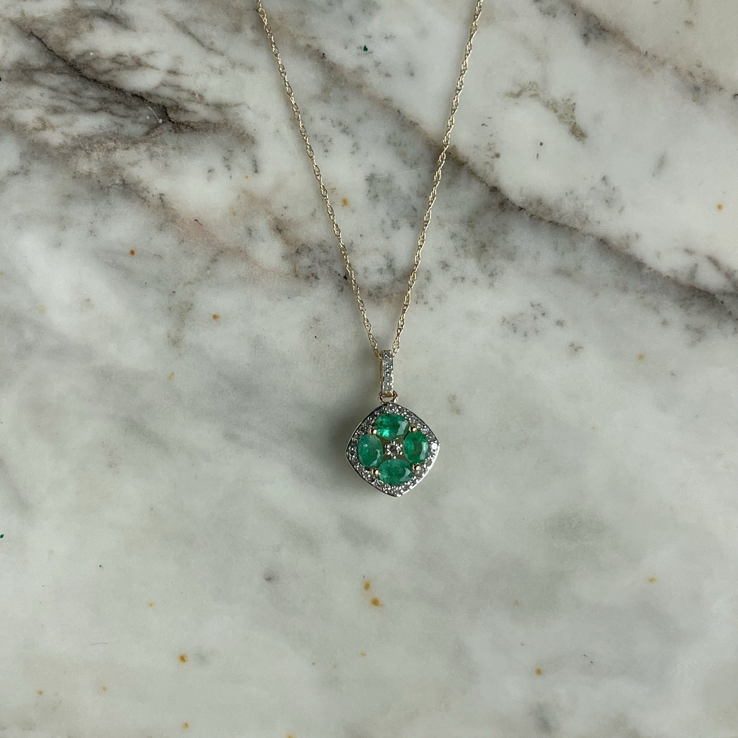 Collar en oro amarillo 14k con dije de esmeraldas en forma de flor y borde de diamantes 0.15ctw