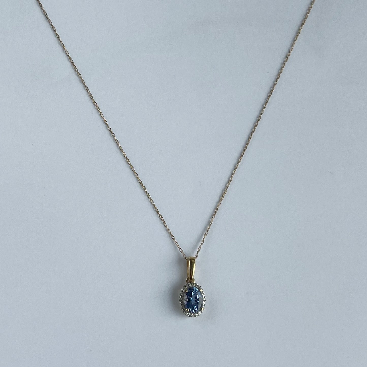 Collar en oro amarillo 10k con dije de tanzanita ovalada y halo de diamantes