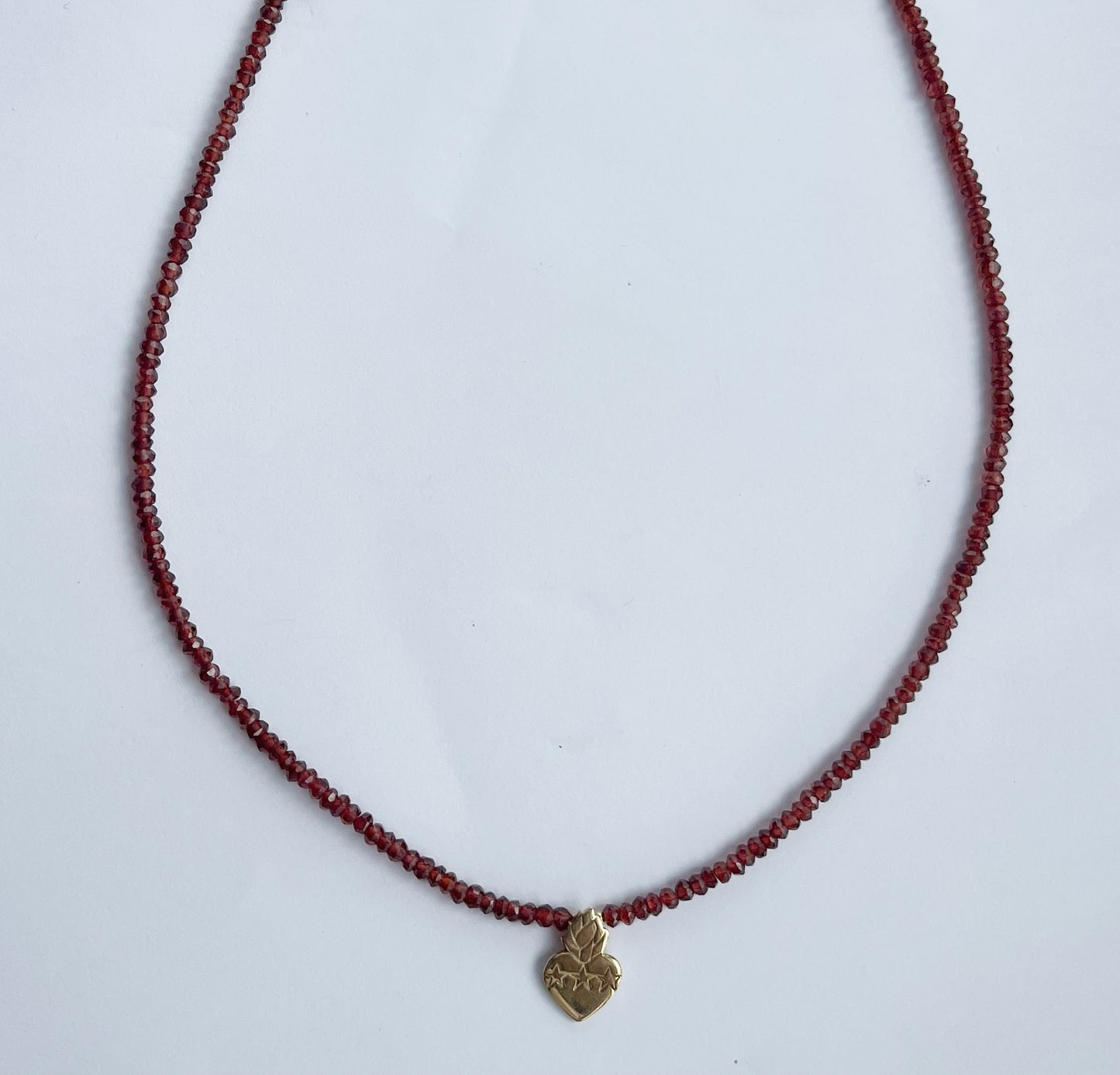 Collar de granates con sagrado corazón en plata con baño de oro amarillo y broche con cadena en goldfill