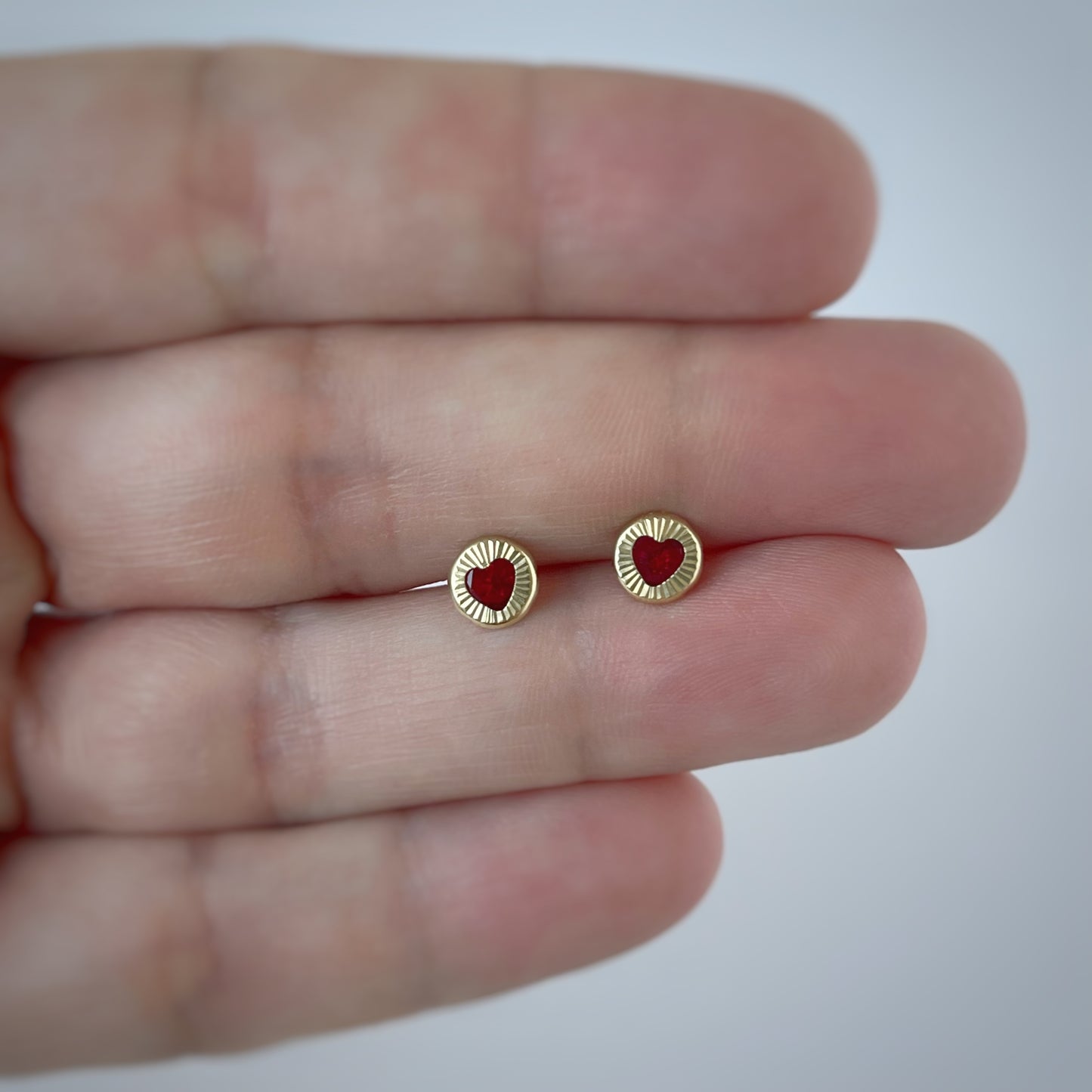 Aretes en oro amarillo 14K con círculo de rayitas y centro con corazón de circonita roja con tope rosca