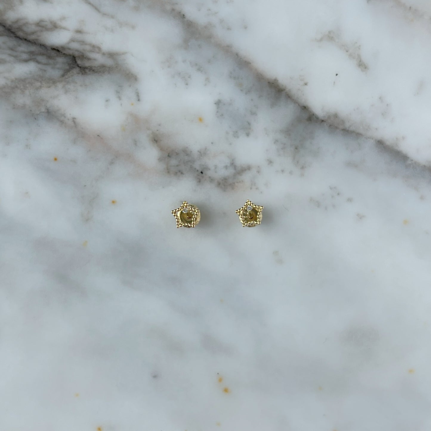 Aretes en oro amarillo 18k estrellita delineada con diamante con broche rosca