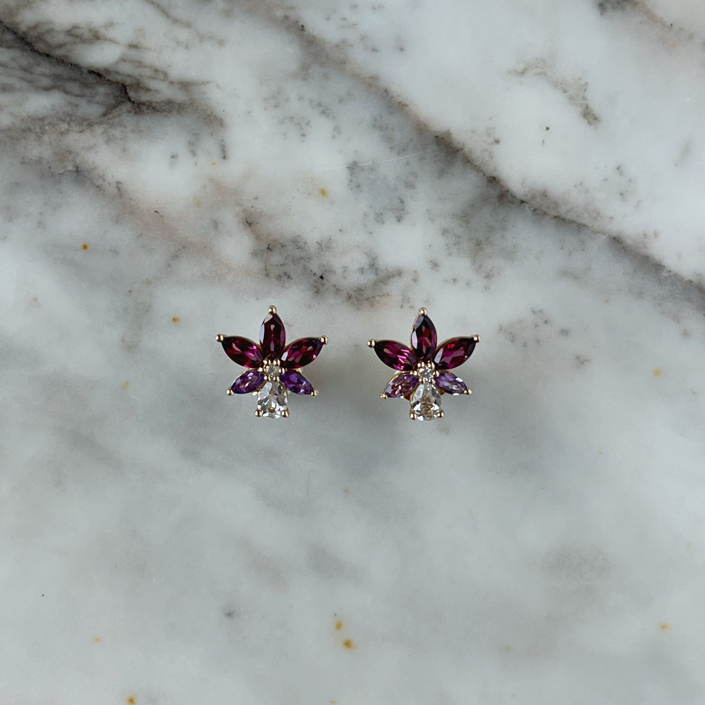 Aretes en oro amarillo 14k con petalos de topacio blanco y granate rhodolite