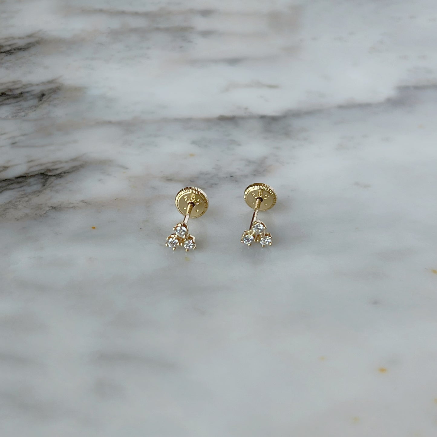 Arete con tres circonitas blancas separadas en oro amarillo de 14K con tope rosca