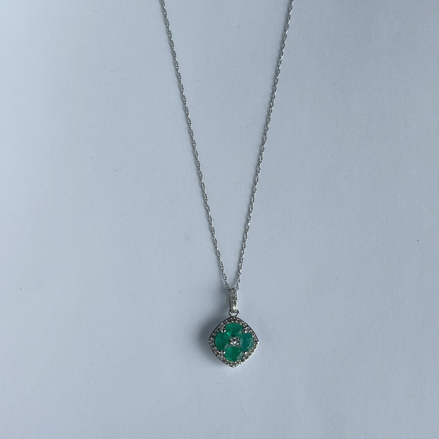 Collar en oro blanco 14k con dije de esmeraldas en forma de flor y borde de diamantes 0.15ctw