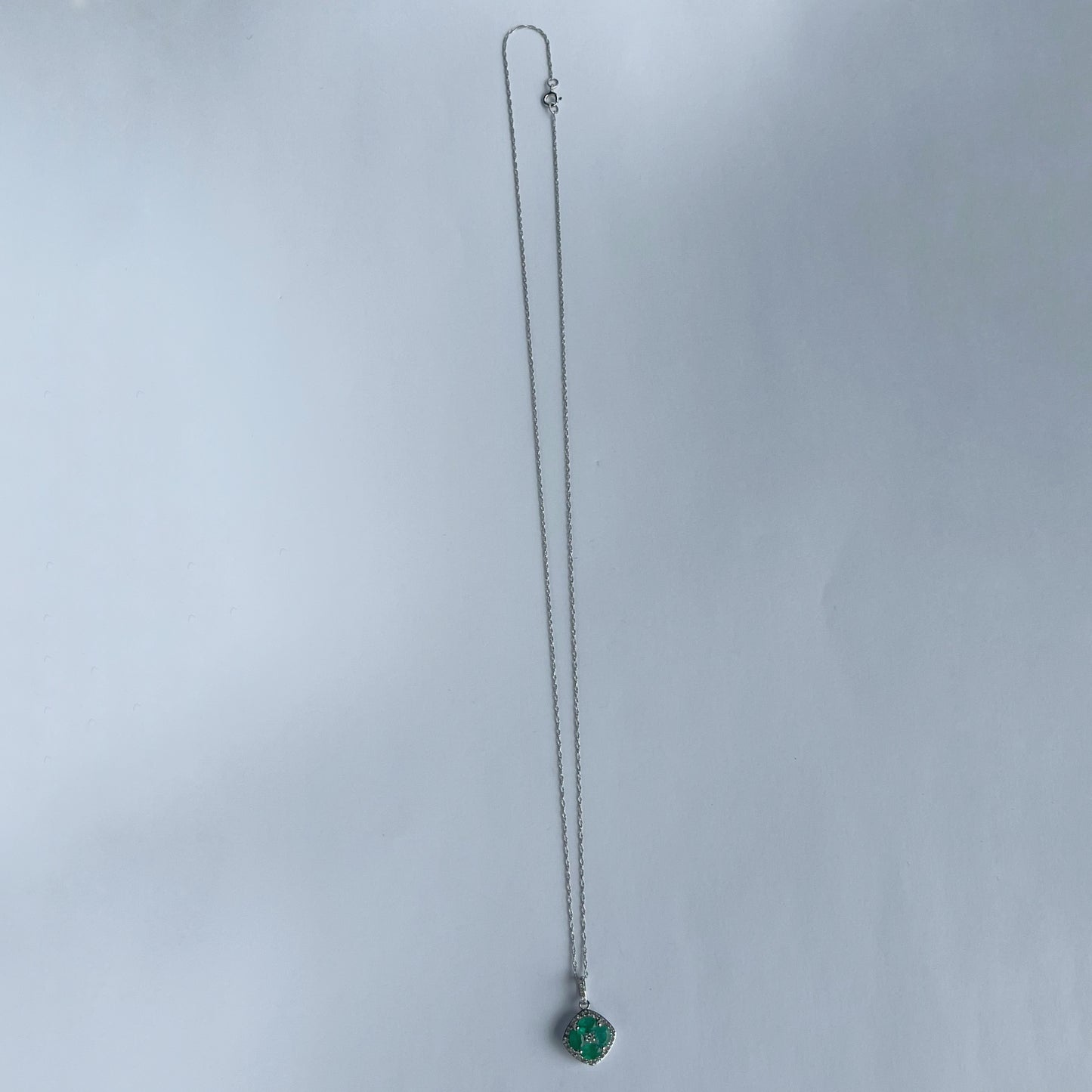 Collar en oro blanco 14k con dije de esmeraldas en forma de flor y borde de diamantes 0.15ctw