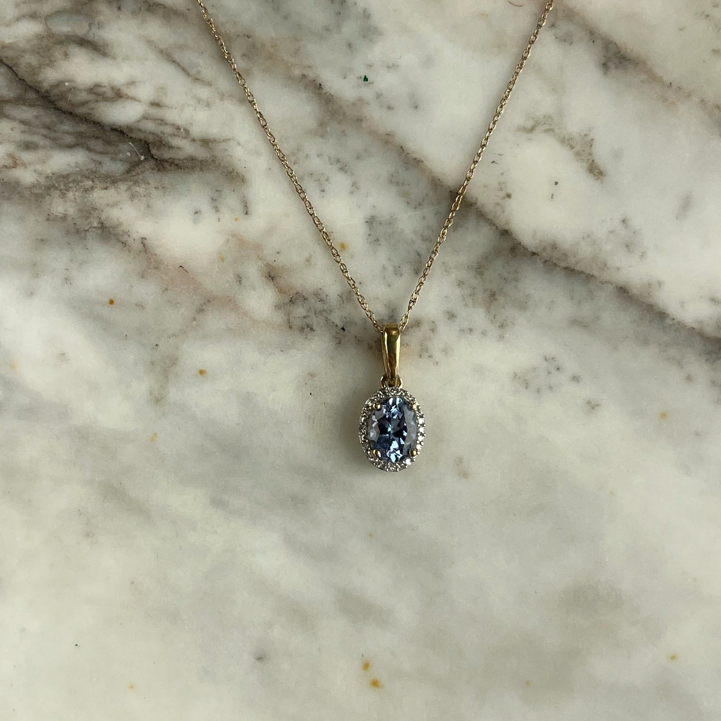 Collar en oro amarillo 10k con dije de tanzanita ovalada y halo de diamantes