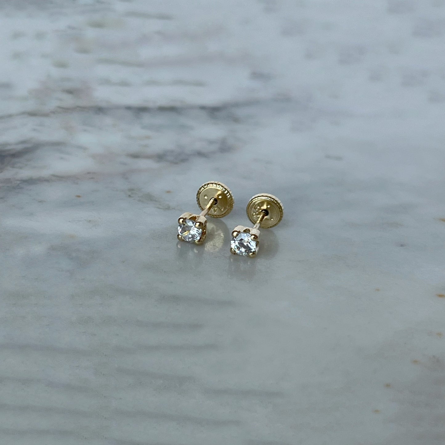 Aretes en oro amarillo 14K con circonita redonda blanca con cuatro agarres con tope rosca