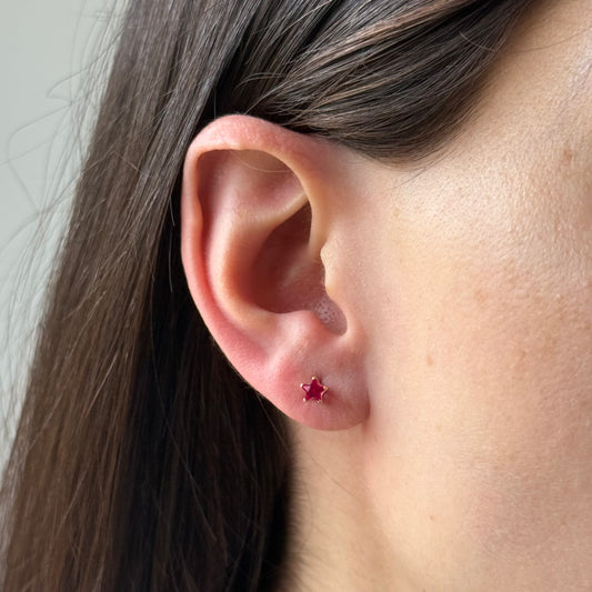 Aretes estrella con circón fucsia en oro amarillo 14K con tope rosca