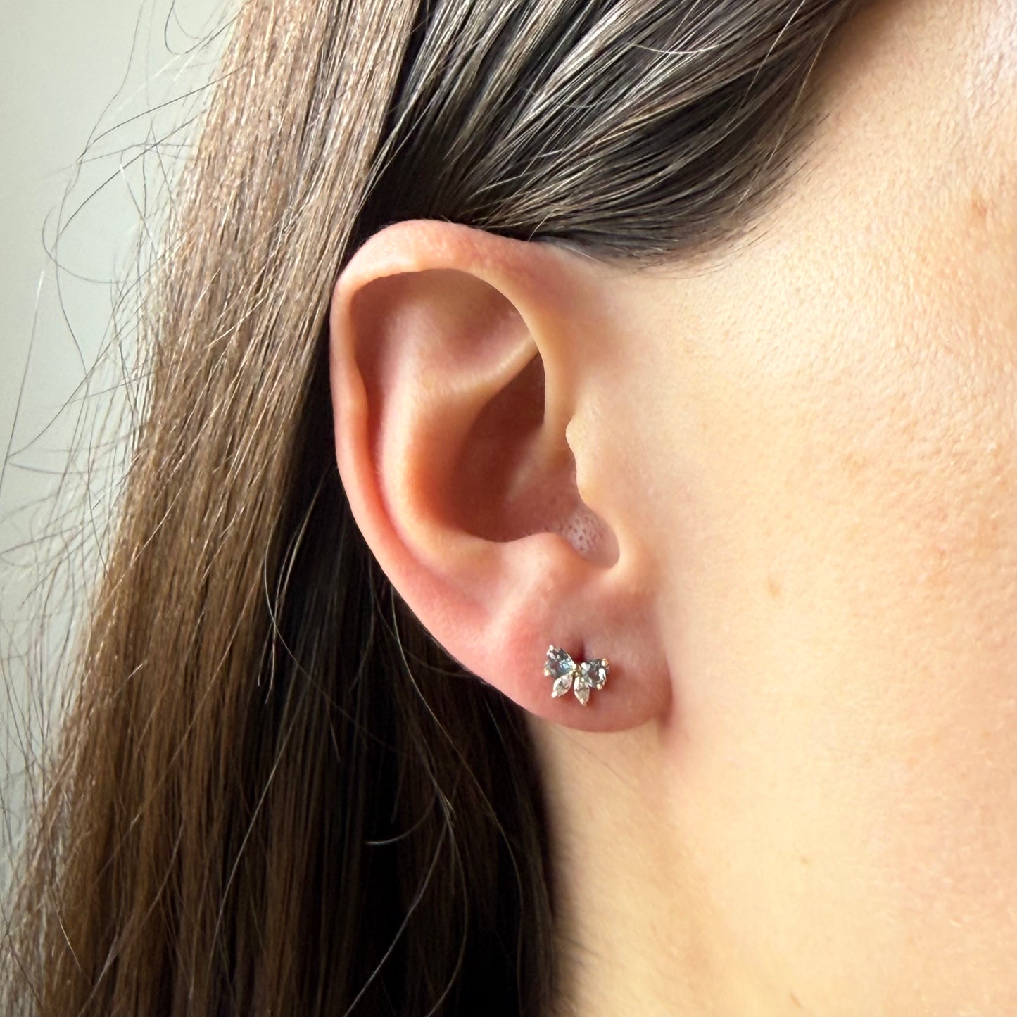 Aretes lazo con circonita celeste y blanca en oro amarillo 14K con tope rosca