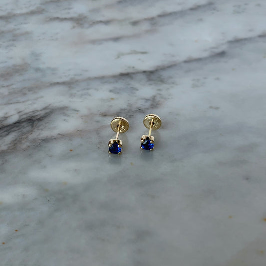 Aretes en oro amarillo 14K con circonita redonda azul con cuatro agarres con tope rosca