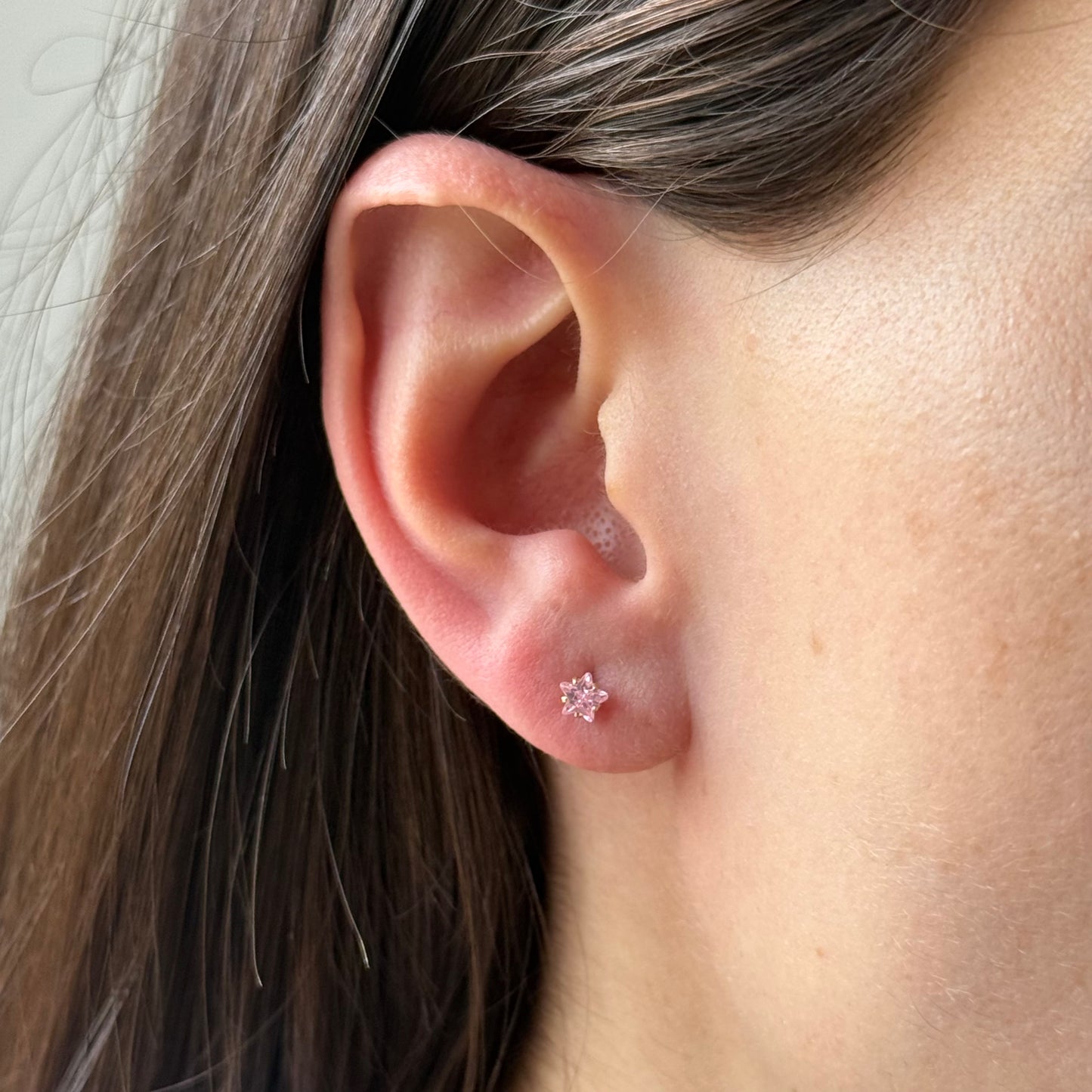 Aretes mini estrella con circón rosado en oro amarillo 14K con tope rosca