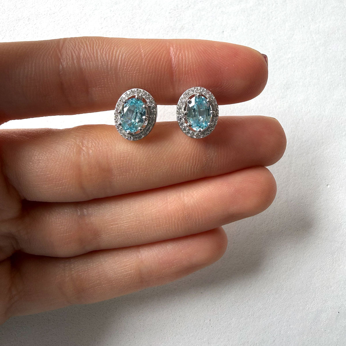 Aretes de plata con topacio azul ovalado y halo de circones