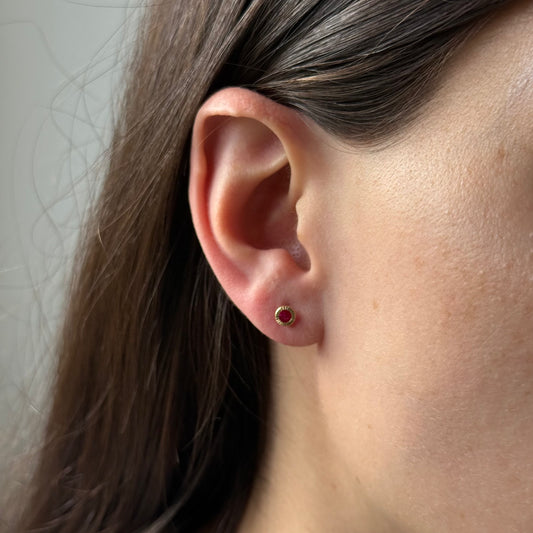 Aretes con circonita redonda fucsia biselada de rayitas en oro amarillo 14k con tope rosca