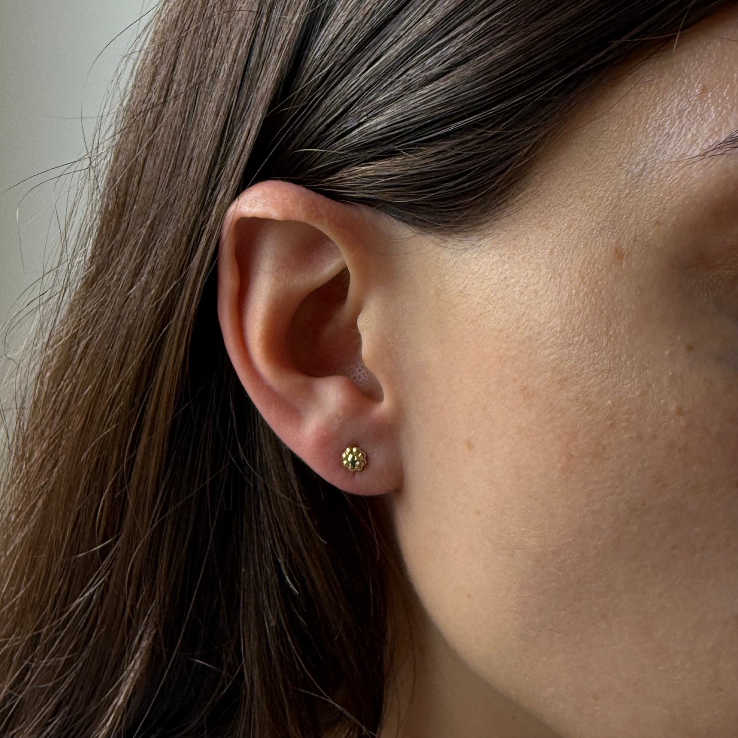 Aretes en oro amarillo 14K con flor de pétalos de oro y circonita azul con tope rosca