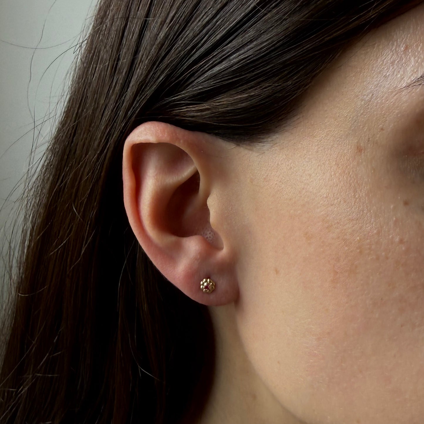 Aretes en oro amarillo 14K con flor de pétalos de oro y circonita fucsia con tope rosca