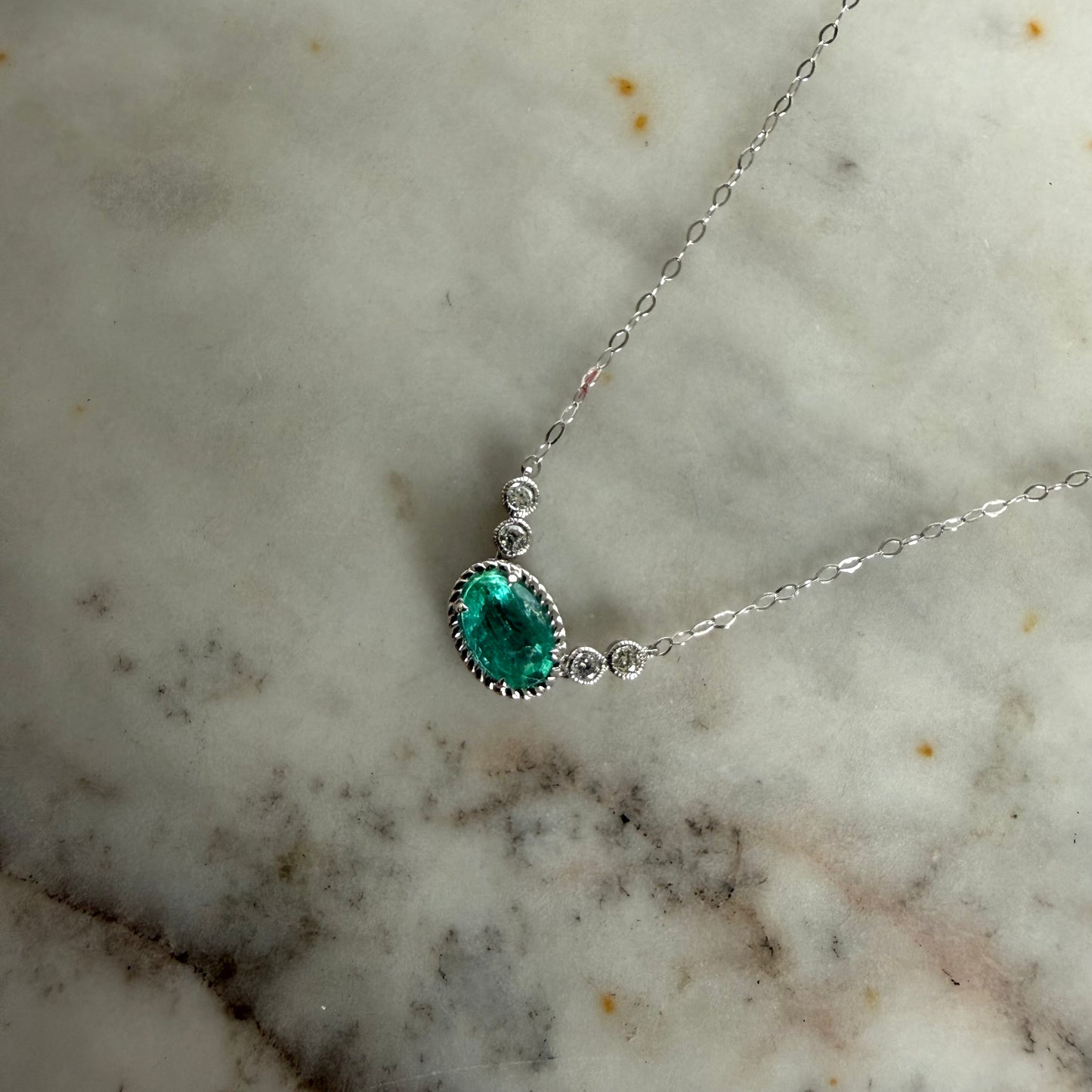 Collar en oro blanco 14K con esmeralda ovalada y diamantes biselados