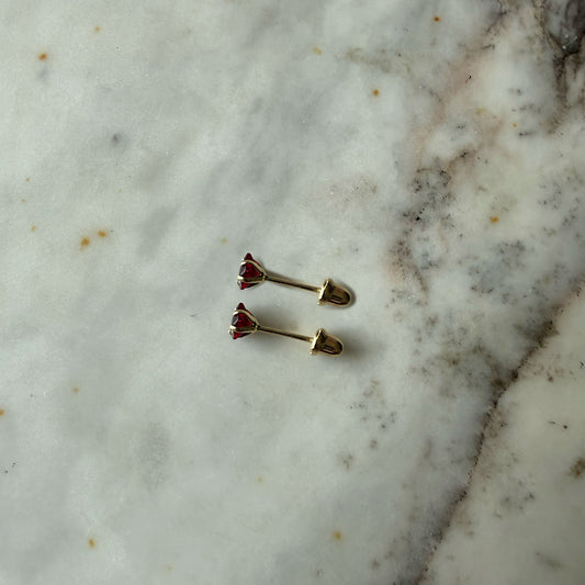 Aretes mini estrella con circón rojo en oro amarillo 14K con tope rosca