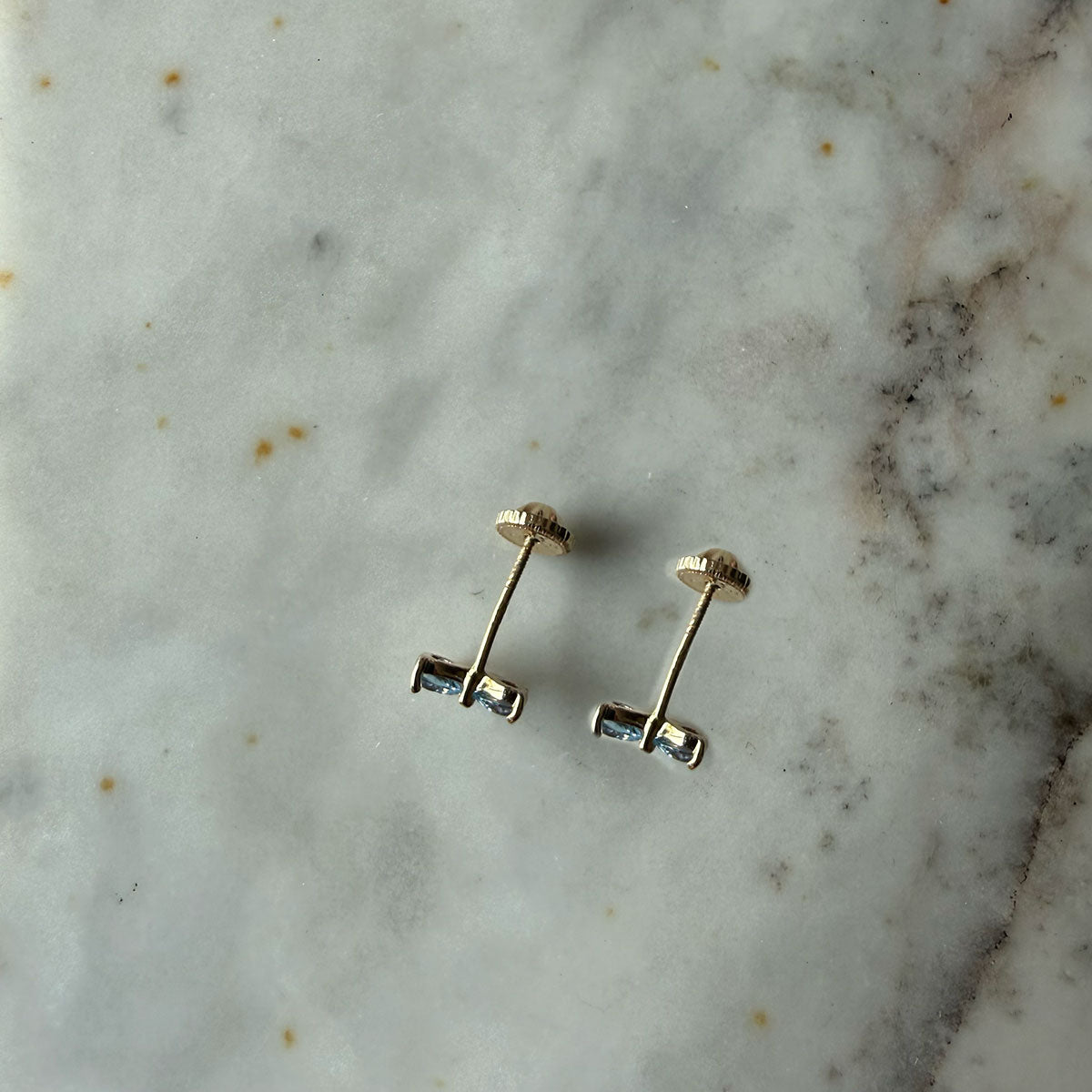 Aretes lazo con circonita celeste y blanca en oro amarillo 14K con tope rosca
