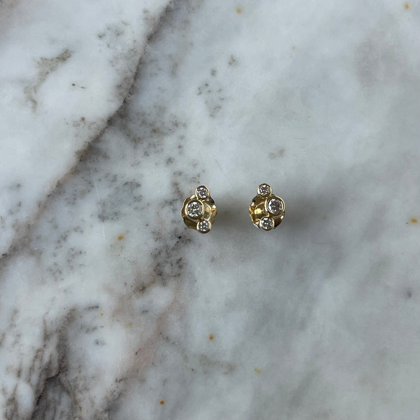 Aretes de tres diamantes redondos biselados 0.18 ctw en oro amarillo 10k