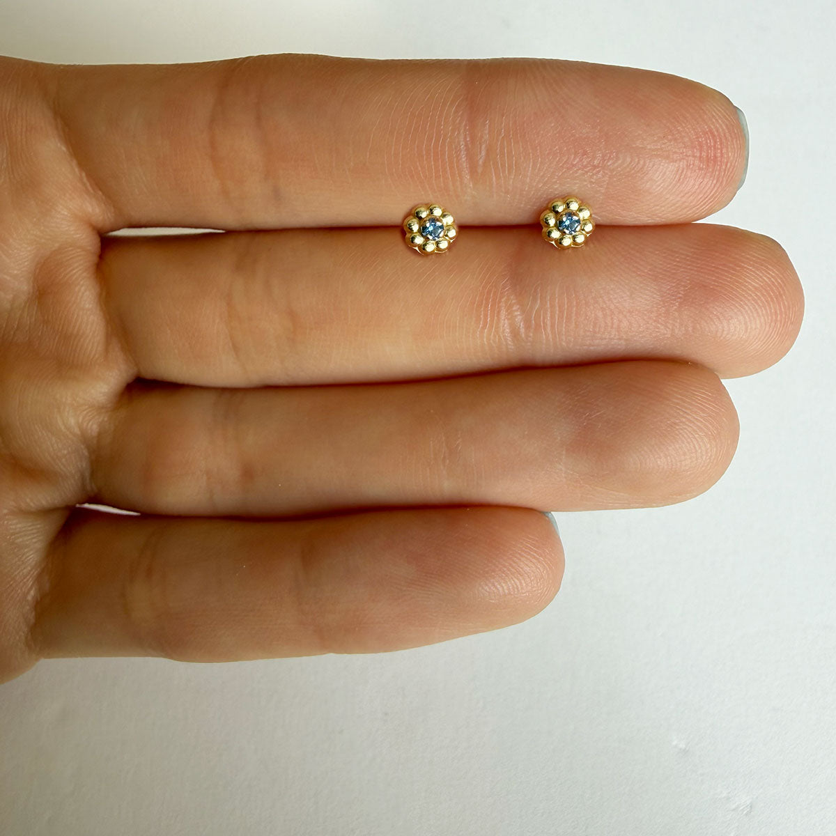 Aretes en oro amarillo 14K con flor de pétalos de oro y circonita azul con tope rosca