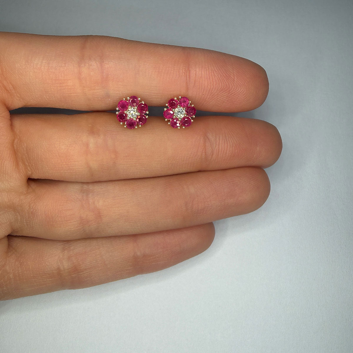 Aretes en oro amarillo 10K en forma de flor con rubíes redondos y diamantes central 0.10ctw