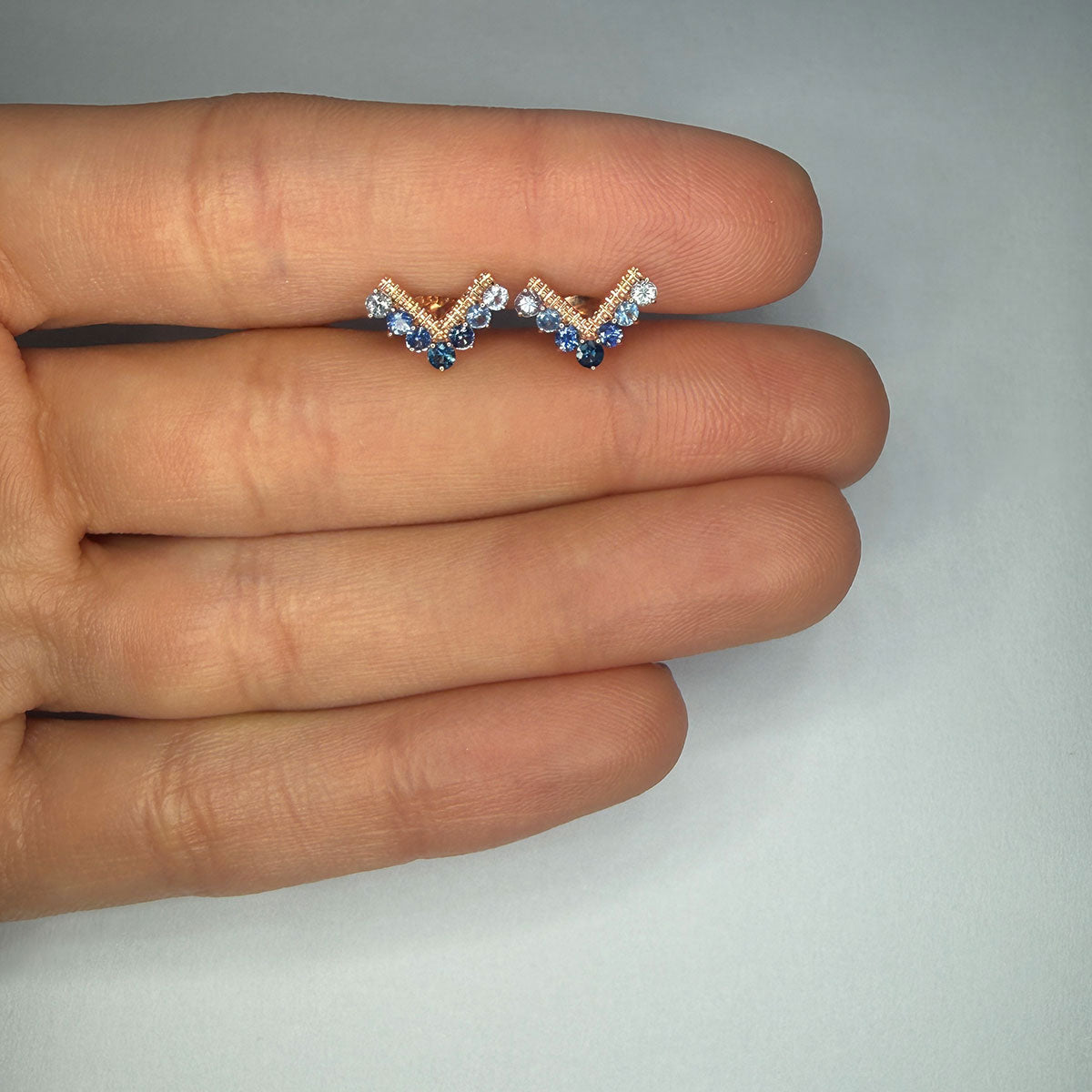 Aretes en forma de V en oro rosa 10K con zafiros y tanzanitas